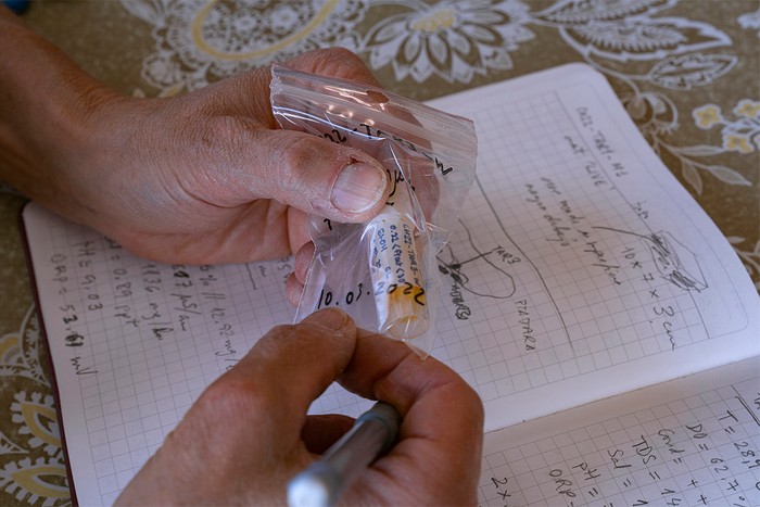 Holding a sample of water in tube over book of notes
