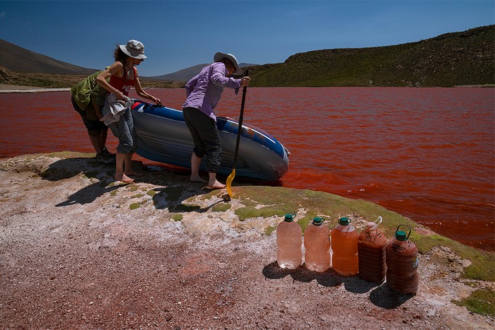 people pull boat off a red lake