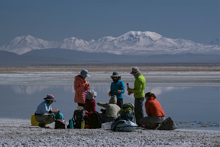 Scientists of lakeside with snow-covered mountains behind