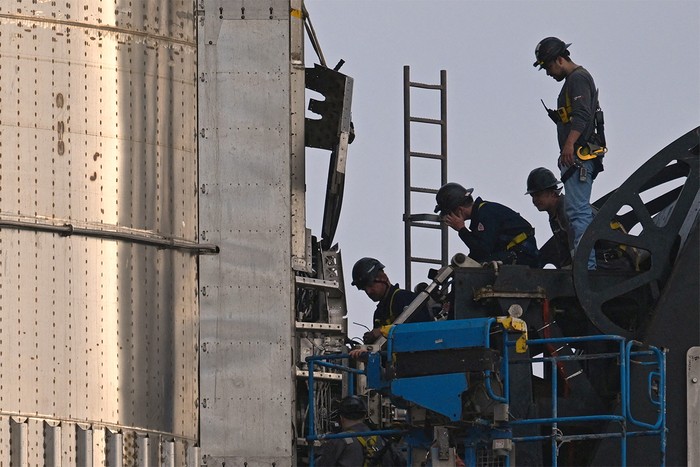 Workmen with ladders examine rocket